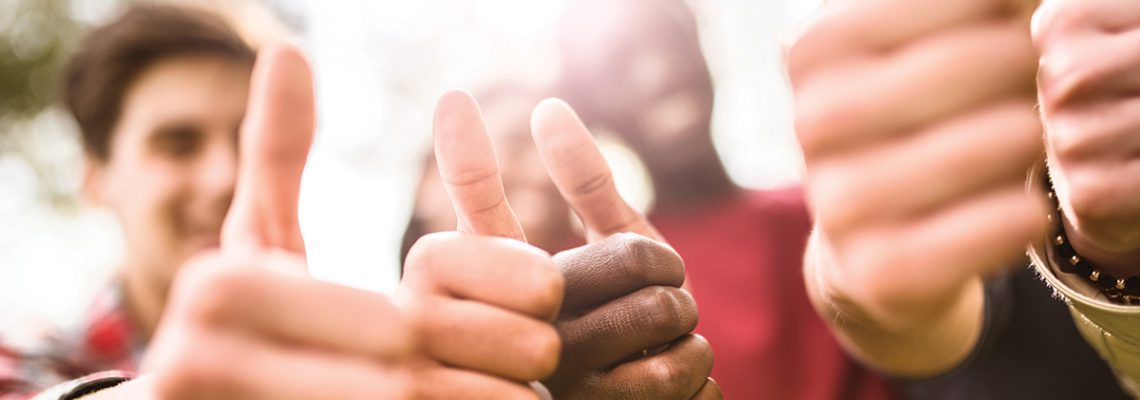 college student multiracial thumbs up at dusk